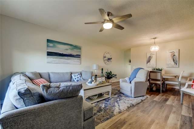 living room with ceiling fan, wood-type flooring, and a textured ceiling