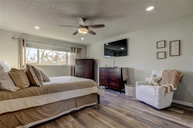 bedroom with hardwood / wood-style flooring, ceiling fan, and a textured ceiling