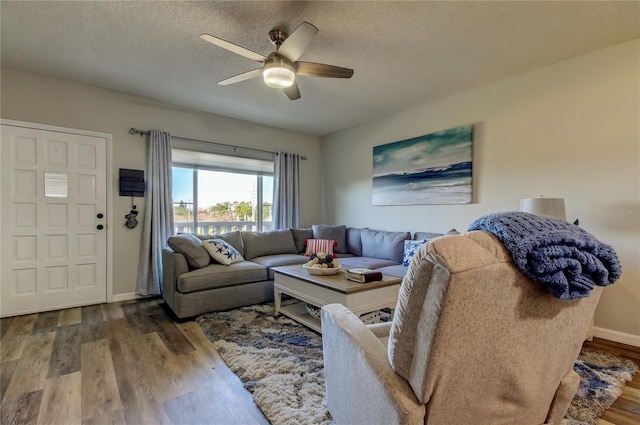 living room with hardwood / wood-style flooring, ceiling fan, and a textured ceiling