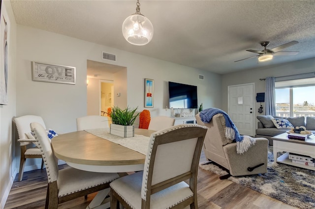 dining space featuring ceiling fan, wood-type flooring, and a textured ceiling