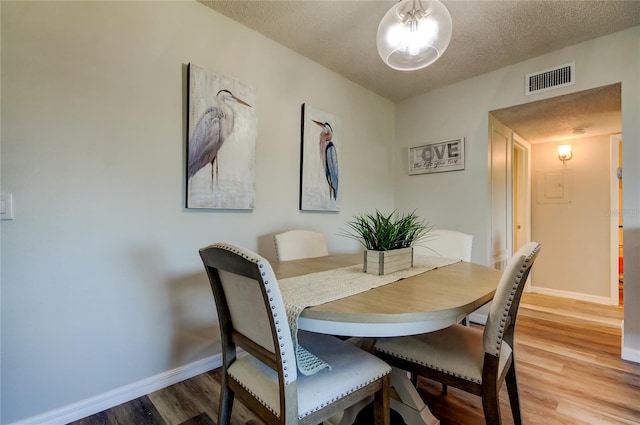 dining space with wood-type flooring and a textured ceiling