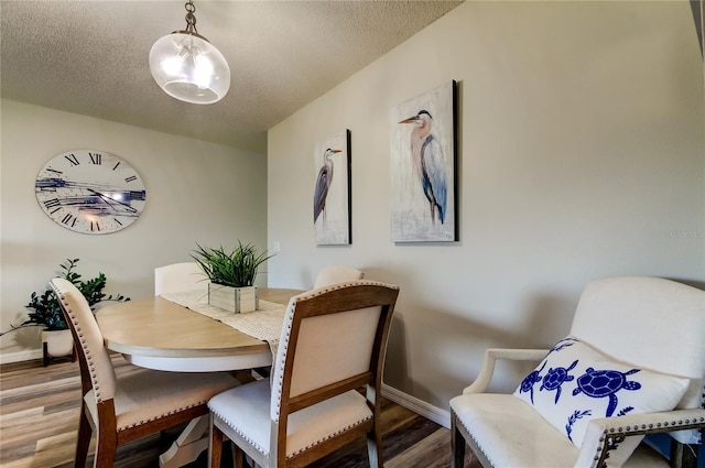 dining room featuring wood-type flooring and a textured ceiling