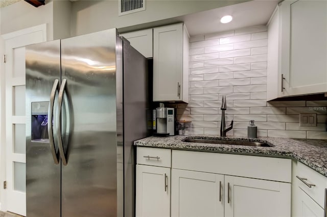 kitchen with sink, decorative backsplash, stainless steel fridge, and white cabinets