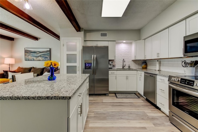 kitchen with sink, appliances with stainless steel finishes, tasteful backsplash, light hardwood / wood-style floors, and white cabinets