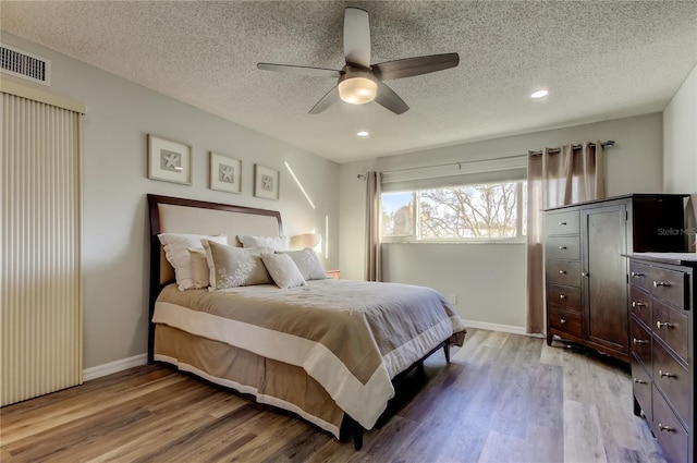 bedroom with ceiling fan, light hardwood / wood-style floors, and a textured ceiling