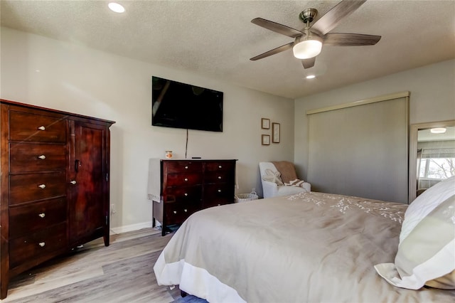 bedroom with ceiling fan, a textured ceiling, and light wood-type flooring