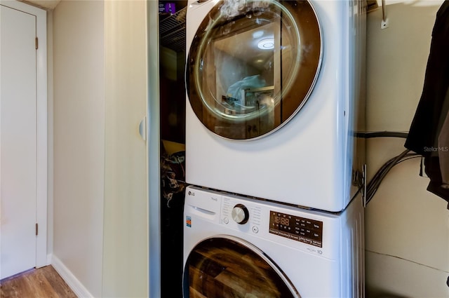 clothes washing area featuring stacked washing maching and dryer and light hardwood / wood-style floors