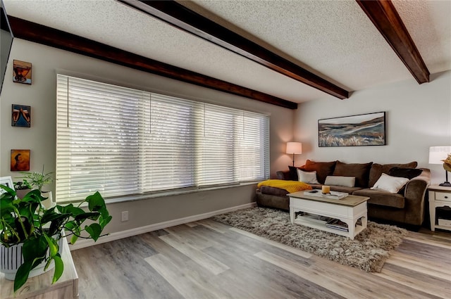 living room featuring beamed ceiling, a textured ceiling, and light wood-type flooring