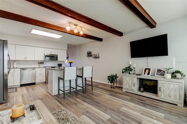 kitchen featuring white cabinetry, stainless steel appliances, a breakfast bar area, and backsplash