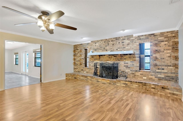 unfurnished living room featuring brick wall, crown molding, a brick fireplace, and light hardwood / wood-style floors