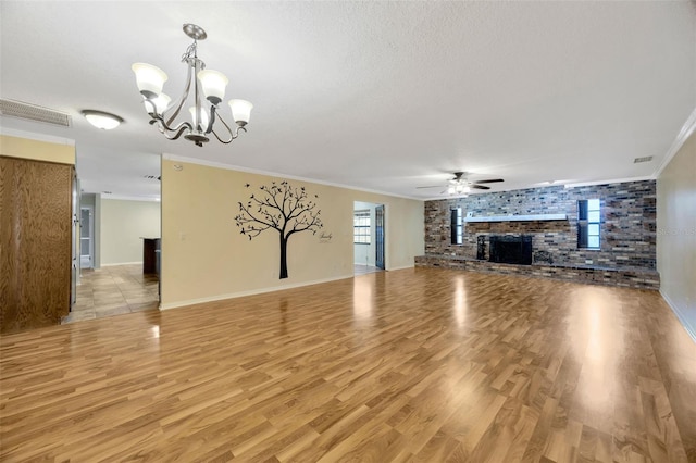 unfurnished living room with crown molding, light hardwood / wood-style floors, a textured ceiling, a brick fireplace, and ceiling fan with notable chandelier