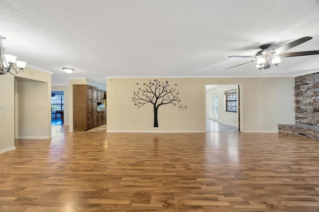 unfurnished living room featuring hardwood / wood-style floors, ceiling fan with notable chandelier, ornamental molding, and a textured ceiling