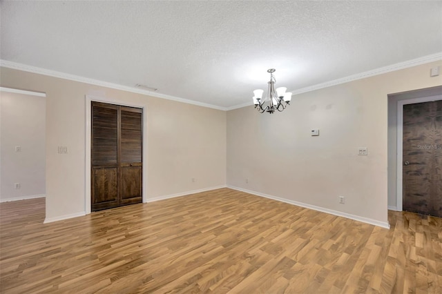 spare room with ornamental molding, a textured ceiling, and light wood-type flooring