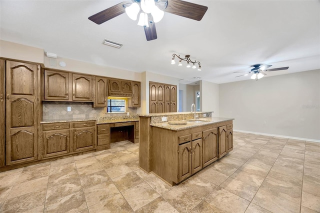 kitchen with sink, built in desk, backsplash, and ceiling fan