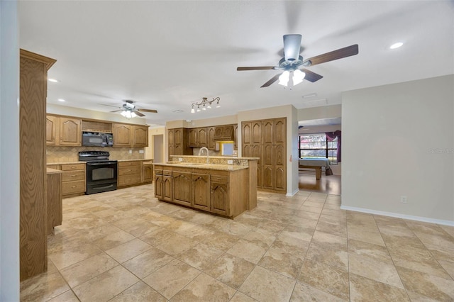 kitchen featuring sink, a center island with sink, ceiling fan, decorative backsplash, and black appliances