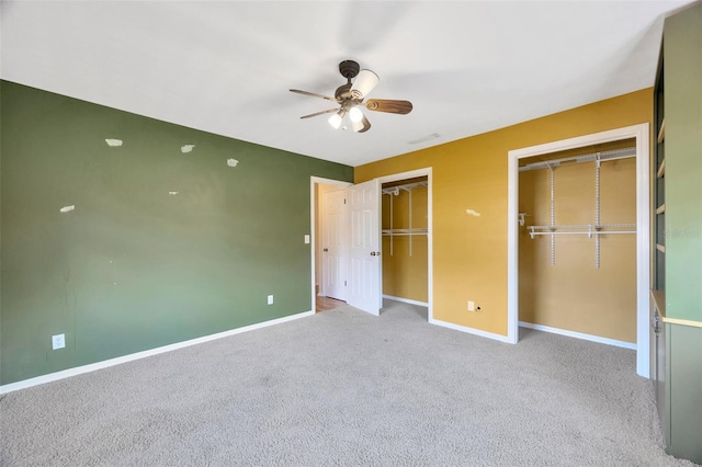 unfurnished bedroom with multiple closets, ceiling fan, and light carpet