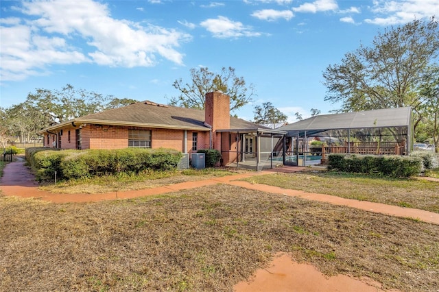 rear view of property with a swimming pool, a yard, cooling unit, and glass enclosure