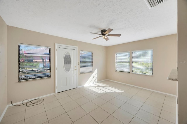 tiled foyer entrance with a textured ceiling and ceiling fan