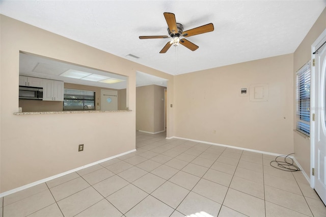 tiled spare room featuring a textured ceiling and ceiling fan