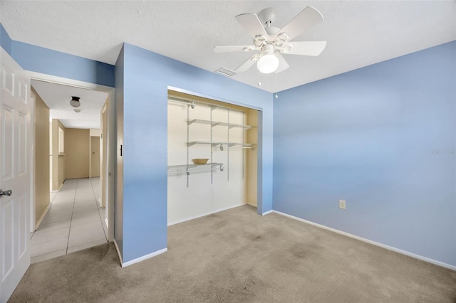 unfurnished bedroom with ceiling fan, a closet, light carpet, and a textured ceiling