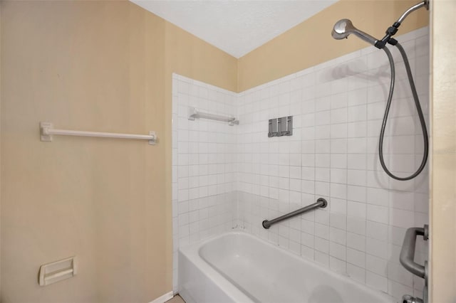 bathroom with tiled shower / bath and a textured ceiling