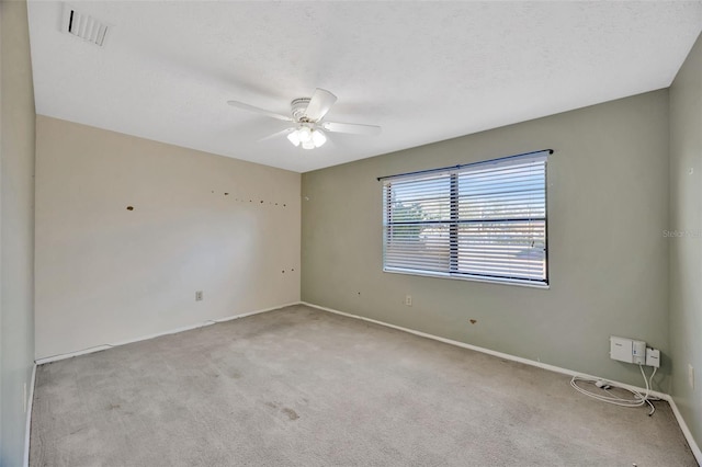 spare room featuring light colored carpet, a textured ceiling, and ceiling fan