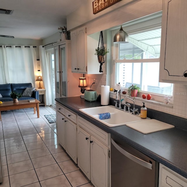 kitchen with white cabinetry, sink, decorative backsplash, stainless steel dishwasher, and light tile patterned floors