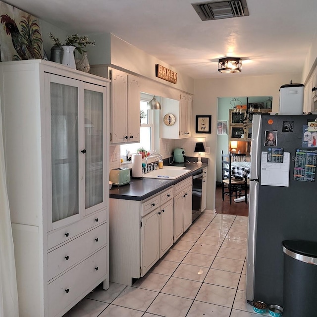 kitchen featuring light tile patterned flooring, sink, stainless steel fridge, dishwasher, and white cabinets