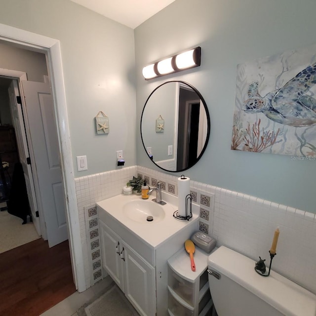 bathroom with vanity, toilet, and tile walls