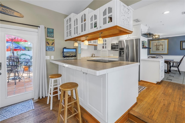 kitchen with white cabinetry, a kitchen breakfast bar, stainless steel appliances, decorative light fixtures, and kitchen peninsula