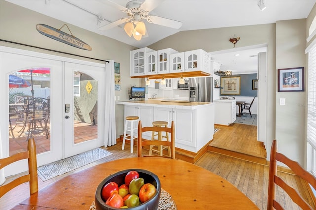 kitchen featuring stainless steel fridge with ice dispenser, white cabinets, light hardwood / wood-style floors, kitchen peninsula, and french doors