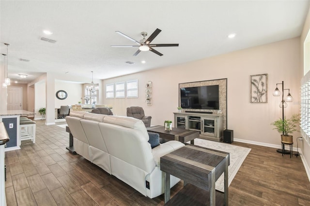 living room with dark wood-type flooring and ceiling fan with notable chandelier