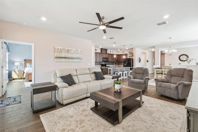 living room featuring ceiling fan with notable chandelier, sink, and hardwood / wood-style floors