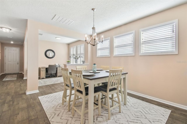 dining area featuring a notable chandelier, dark hardwood / wood-style floors, and a textured ceiling