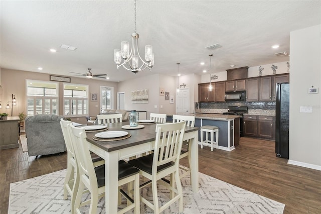 dining space featuring dark hardwood / wood-style flooring, ceiling fan with notable chandelier, and a textured ceiling