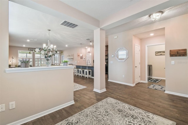 foyer entrance featuring dark wood-type flooring, sink, and a chandelier