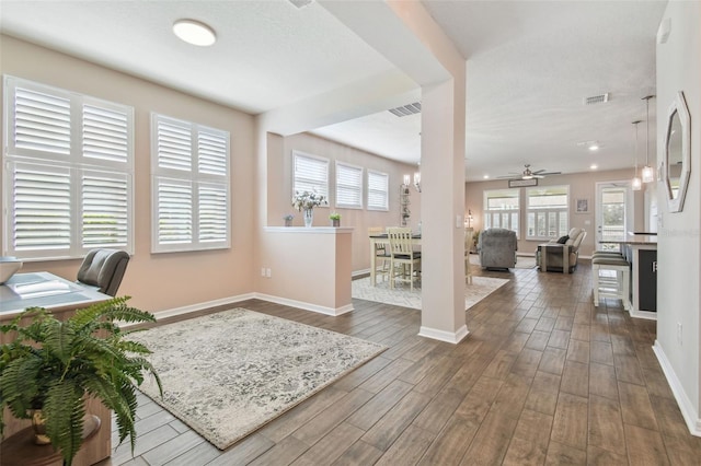 office space featuring ceiling fan with notable chandelier, a wealth of natural light, and dark hardwood / wood-style floors