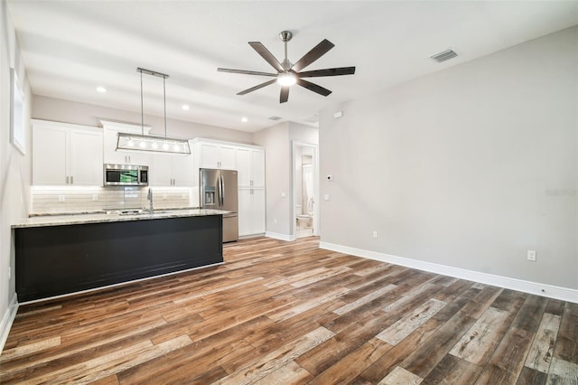 kitchen with tasteful backsplash, hanging light fixtures, appliances with stainless steel finishes, light stone countertops, and white cabinets