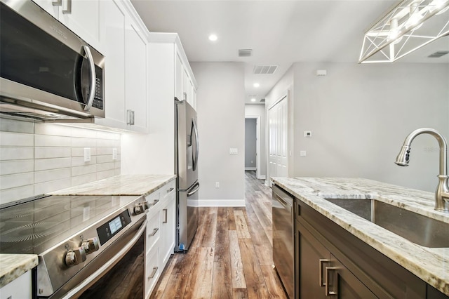 kitchen featuring white cabinetry, sink, stainless steel appliances, and light stone countertops