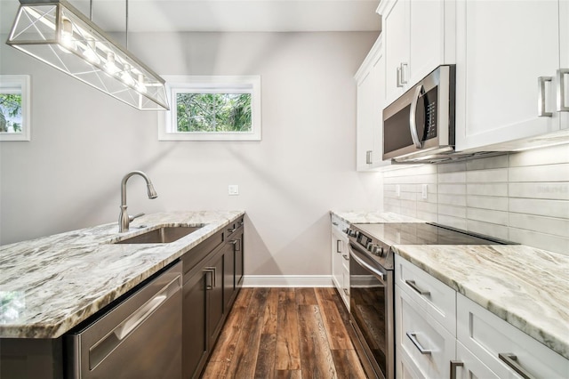 kitchen featuring sink, white cabinetry, stainless steel appliances, decorative backsplash, and decorative light fixtures