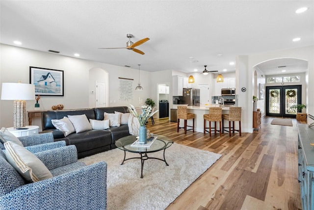 living room with french doors, ceiling fan, and light hardwood / wood-style flooring