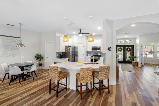 kitchen with stainless steel appliances, white cabinetry, pendant lighting, and a kitchen breakfast bar