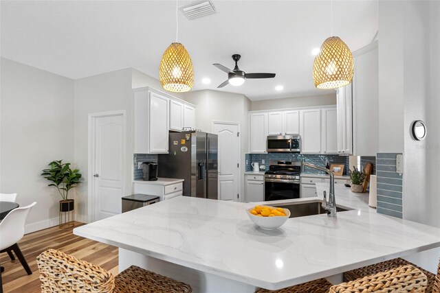 kitchen featuring appliances with stainless steel finishes, sink, white cabinets, and kitchen peninsula