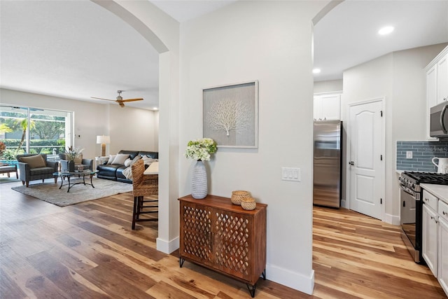 kitchen with stainless steel appliances, white cabinetry, and light wood-type flooring