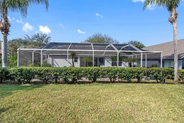 rear view of property featuring a yard and glass enclosure