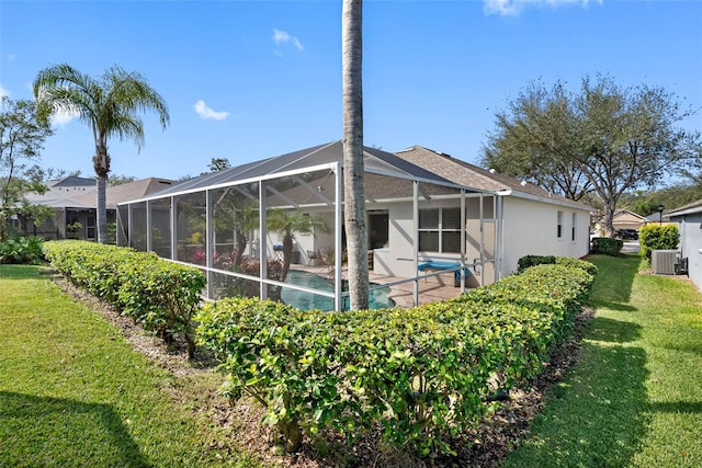 back of house with a yard, a lanai, and central air condition unit