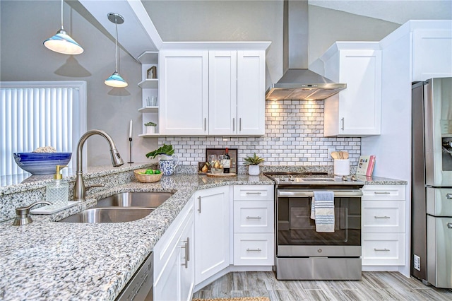 kitchen featuring wall chimney range hood, sink, appliances with stainless steel finishes, white cabinetry, and light stone countertops