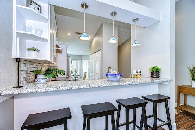 kitchen with light stone counters, decorative light fixtures, dark hardwood / wood-style flooring, and a breakfast bar