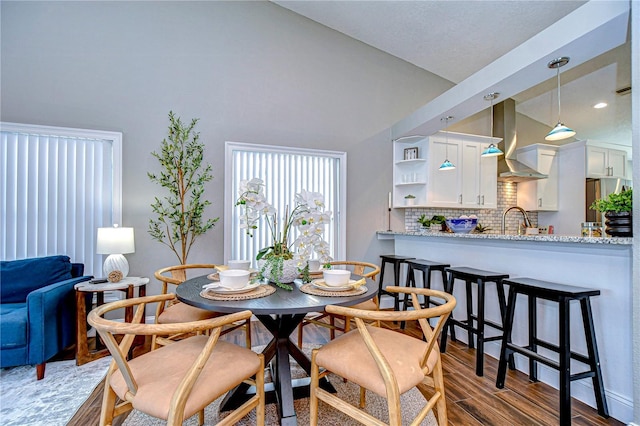 dining room with sink, vaulted ceiling, and dark hardwood / wood-style floors