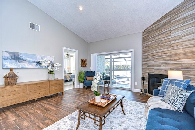 living room with dark wood-type flooring, a tile fireplace, and a textured ceiling